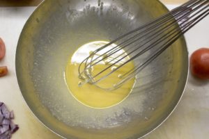 whisk in a bowl with dressing