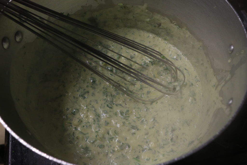 whisking together ingredients for spinach and artichoke dip