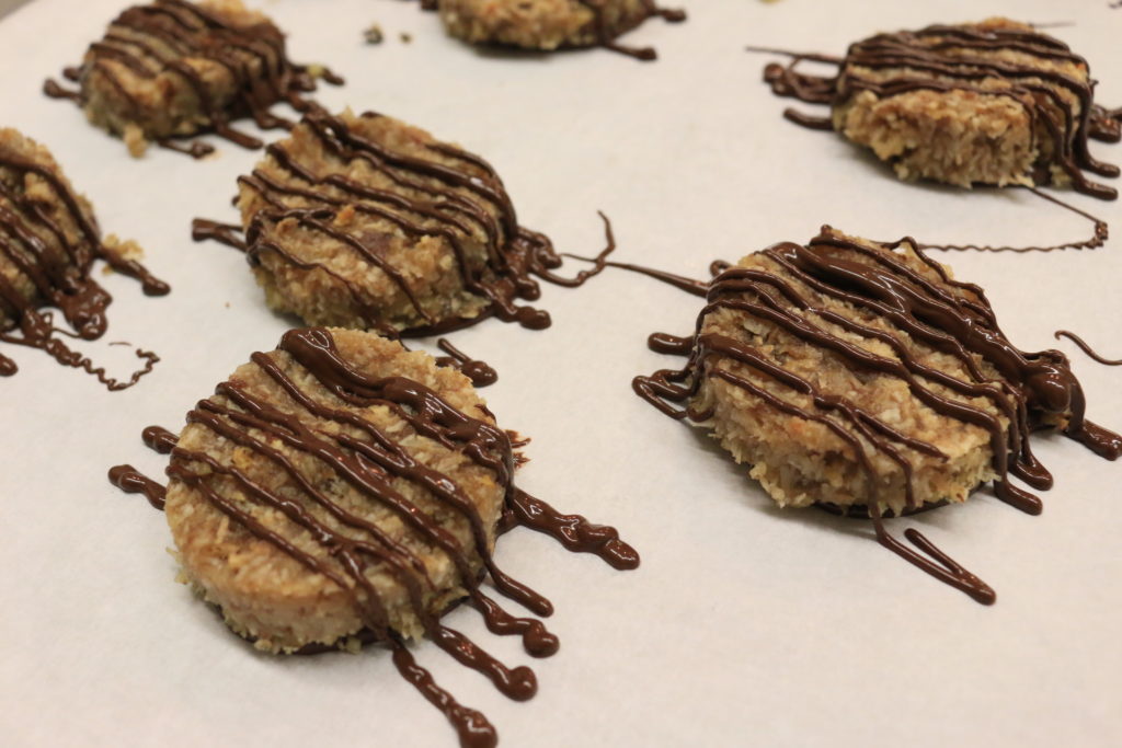 A tray of finished paleo samoa cookies topped with chocolate drizzle.