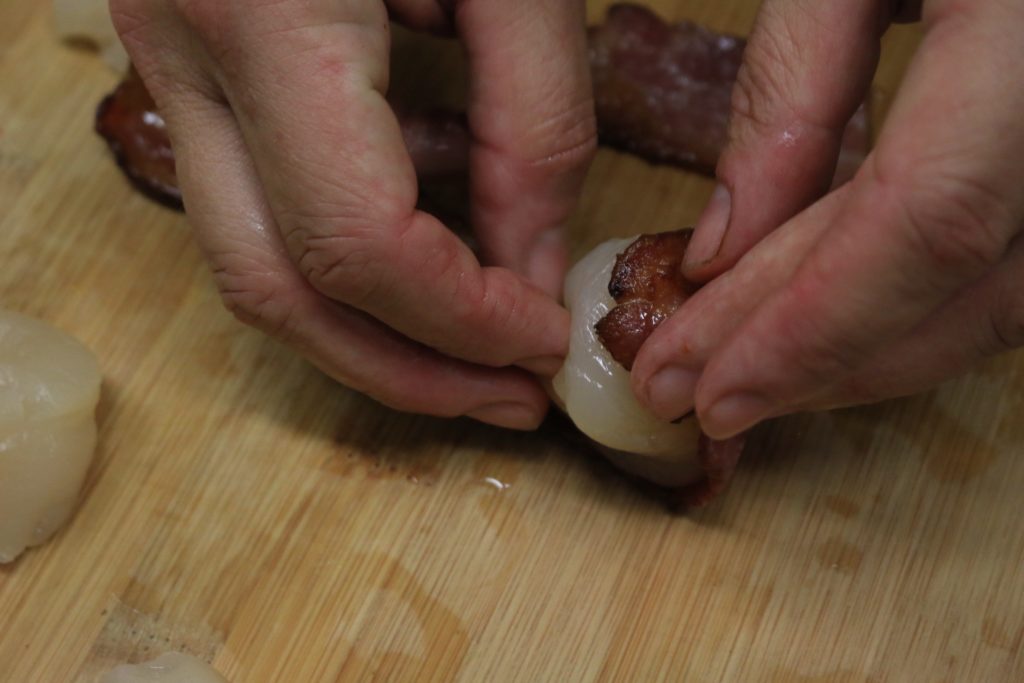 The chef prepares bacon wrapped scallops.